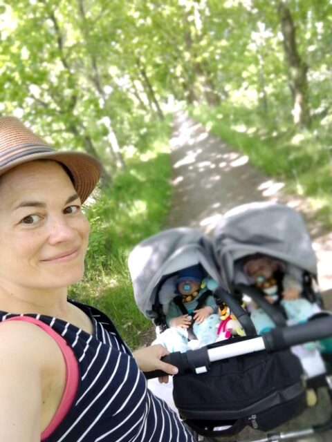 Katharina Mauder schiebt einen Zwillingskinderwagen einen langen Waldweg entlang.